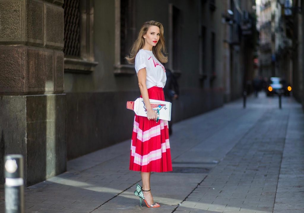 Let us swing - Alexandra Lapp wearing a pleated skirt from Valentino, white t-shirt from Valentino with label print written over the chest with red lipstick, high heel sandals from Sophia Webstar with butterflies on the back, handbag in shape of toothpaste from Yazbukey on November 27, 2017 in Barcelona, Spain.