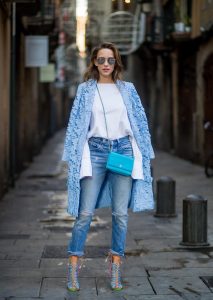 Street Style In Barcelona BARCELONA, SPAIN - NOVEMBER 29: Alexandra Lapp wearing white off-shoulder blouse and light blue lace coat with flowers from Steffen Schraut, silver mirrored sunglasses from Le Specs, multicolored Sophia Webster sandals heels, vintage Levis from ReDone and Chanel purse bag with a long golden strap and Chanel sign in front on November 29, 2017 in Barcelona, Spain.