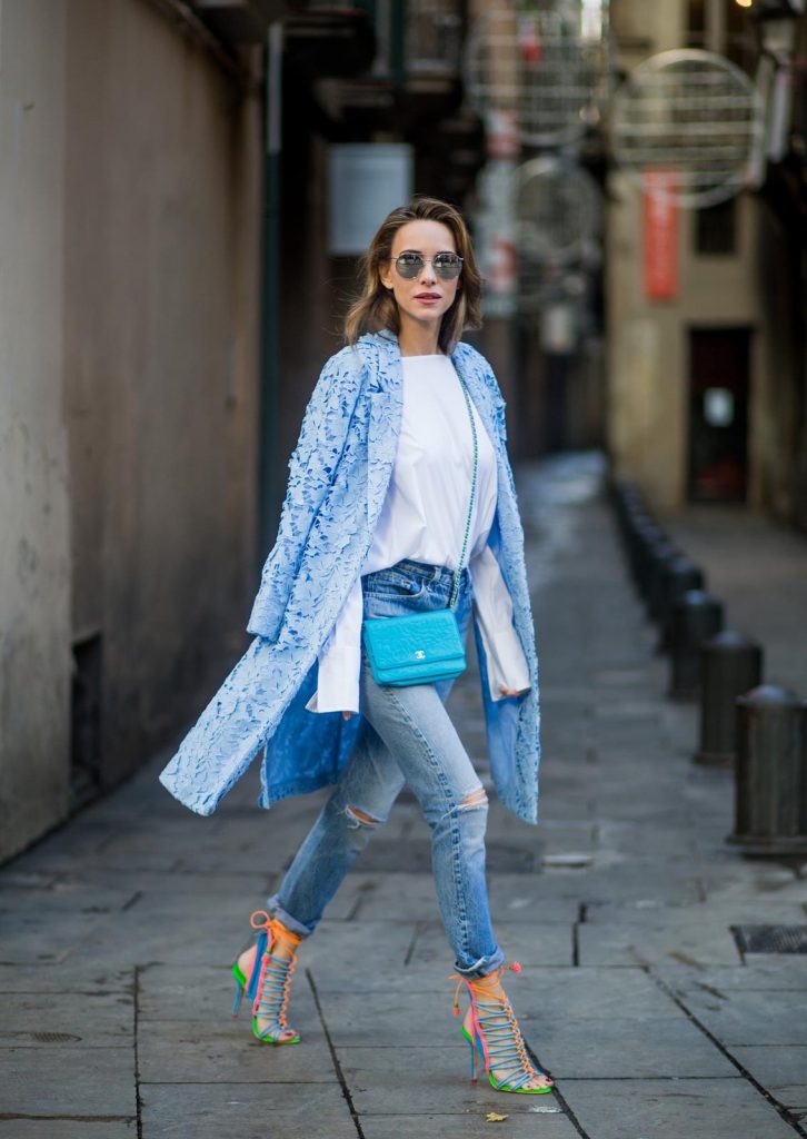 Street Style In Barcelona BARCELONA, SPAIN - NOVEMBER 29: Alexandra Lapp wearing white off-shoulder blouse and light blue lace coat with flowers from Steffen Schraut, silver mirrored sunglasses from Le Specs, multicolored Sophia Webster sandals heels, vintage Levis from ReDone and Chanel purse bag with a long golden strap and Chanel sign in front on November 29, 2017 in Barcelona, Spain.