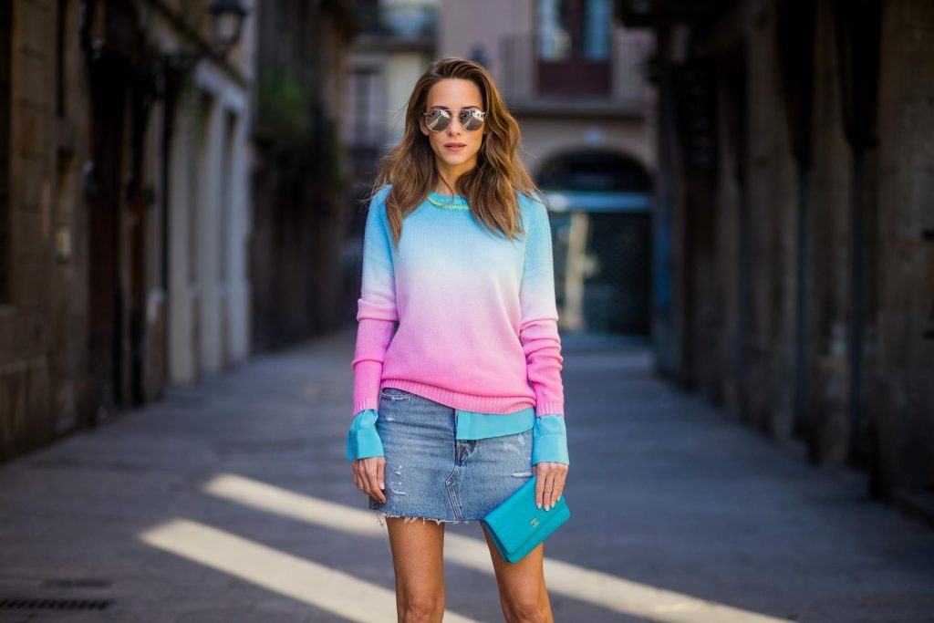 Alexandra Lapp wearing shades of pastels, a mini jeans skirt from Levis, batik cashmere pullover from Heartbreaker in turquoise and pink, Equipment silk blouse in turquoise, little purse bag from Chanel with golden Chanel sign, silver mirrored sunglasses from Le Specs and pink patent So Kate heels from Christian Louboutin on November 28, 2017 in Barcelona, Spain. 