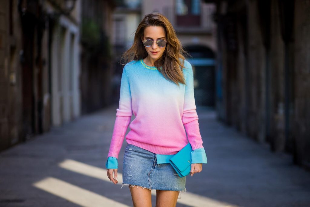 Alexandra Lapp wearing shades of pastels, a mini jeans skirt from Levis, batik cashmere pullover from Heartbreaker in turquoise and pink, Equipment silk blouse in turquoise, little purse bag from Chanel with golden Chanel sign, silver mirrored sunglasses from Le Specs and pink patent So Kate heels from Christian Louboutin on November 28, 2017 in Barcelona, Spain. 