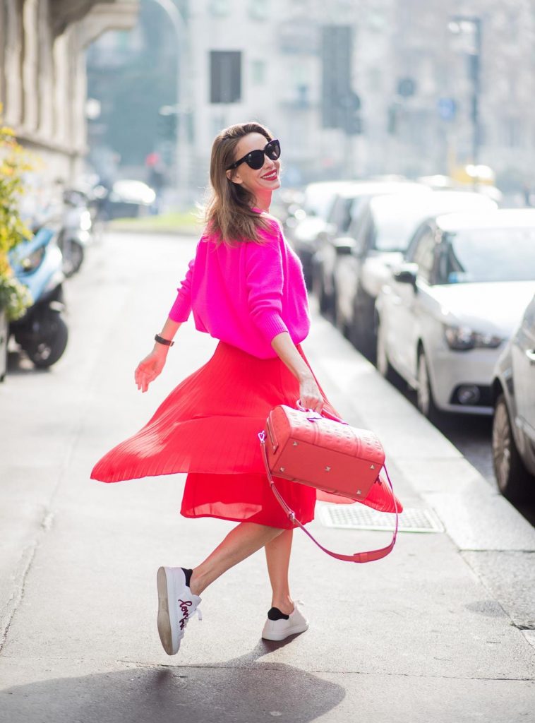 MILAN, ITALY - FEBRUARY 21: Model and Blogger Alexandra Lapp wearing pink and red, a red pleated skirt fro SET, pink cashmere pullover from Jadicted, sneakers from Steffen Schraut, Audrey sunglasses in black from Céline and Boston bag in red from MCM during Milan Fashion Week Fall/Winter 2018/19 on February 21, 2018 in Milan, Italy.