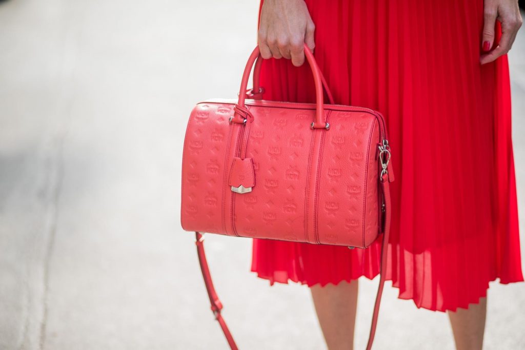 MILAN, ITALY - FEBRUARY 21: Model and Blogger Alexandra Lapp wearing pink and red, a red pleated skirt fro SET, pink cashmere pullover from Jadicted, sneakers from Steffen Schraut, Audrey sunglasses in black from Céline and Boston bag in red from MCM during Milan Fashion Week Fall/Winter 2018/19 on February 21, 2018 in Milan, Italy.