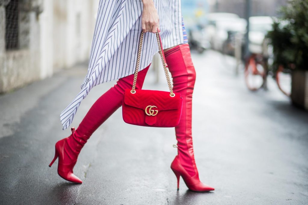 Alexandra Lapp wearing an asymmetric striped blouse by Off-white, red leather over knee boots from Fendi, a red velvet Gucci Marmont handbag with a golden chain and black sunglasses from Celine seen during Milan Fashion Week Fall/Winter 2018/19 on February 24, 2018 in Milan, Italy.