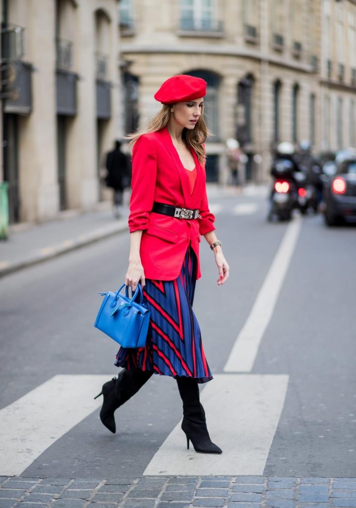 Alexandra Lapp wearing a long red blazer from Zara, a silk top from Jadicted, Collier de chien - a black waist belt with a silver buckle from Hermes, a blue Neo Milla handbag from MCM, a pleated skirt in blue with red stripes from H&M, black boots from Isabel Marant is seen on February 27, 2018 in Paris, France.