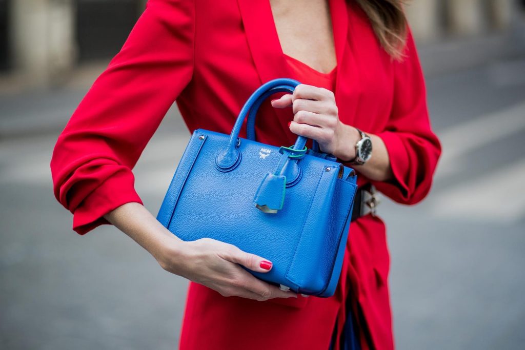 Alexandra Lapp wearing a long red blazer from Zara, a silk top from Jadicted, Collier de chien - a black waist belt with a silver buckle from Hermes, a blue Neo Milla handbag from MCM, a pleated skirt in blue with red stripes from H&M, black boots from Isabel Marant is seen on February 27, 2018 in Paris, France.