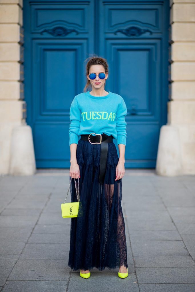 Alexandra Lapp wearing a turquoise pullover with a neon print Tuesday by Alberta Ferretti, a playful dress in black floral lace from Self-Portrait, black waist belt with big buckle from Dorothee Schumacher, blue mirrored sunglasses from Mykita, neon yellow pumps from Christian Louboutin and matching neon yellow handbag from Yves Saint Laurent is seen on February 28, 2018 in Paris, France.