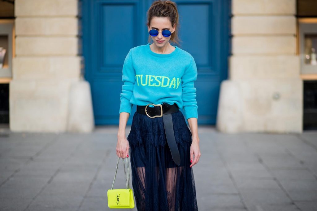 Alexandra Lapp wearing a turquoise pullover with a neon print Tuesday by Alberta Ferretti, a playful dress in black floral lace from Self-Portrait, black waist belt with big buckle from Dorothee Schumacher, blue mirrored sunglasses from Mykita, neon yellow pumps from Christian Louboutin and matching neon yellow handbag from Yves Saint Laurent is seen on February 28, 2018 in Paris, France.