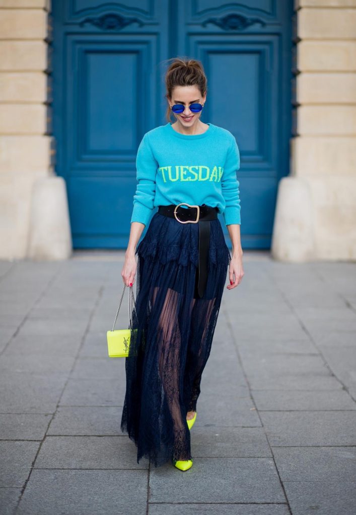 Alexandra Lapp wearing a turquoise pullover with a neon print Tuesday by Alberta Ferretti, a playful dress in black floral lace from Self-Portrait, black waist belt with big buckle from Dorothee Schumacher, blue mirrored sunglasses from Mykita, neon yellow pumps from Christian Louboutin and matching neon yellow handbag from Yves Saint Laurent is seen on February 28, 2018 in Paris, France.