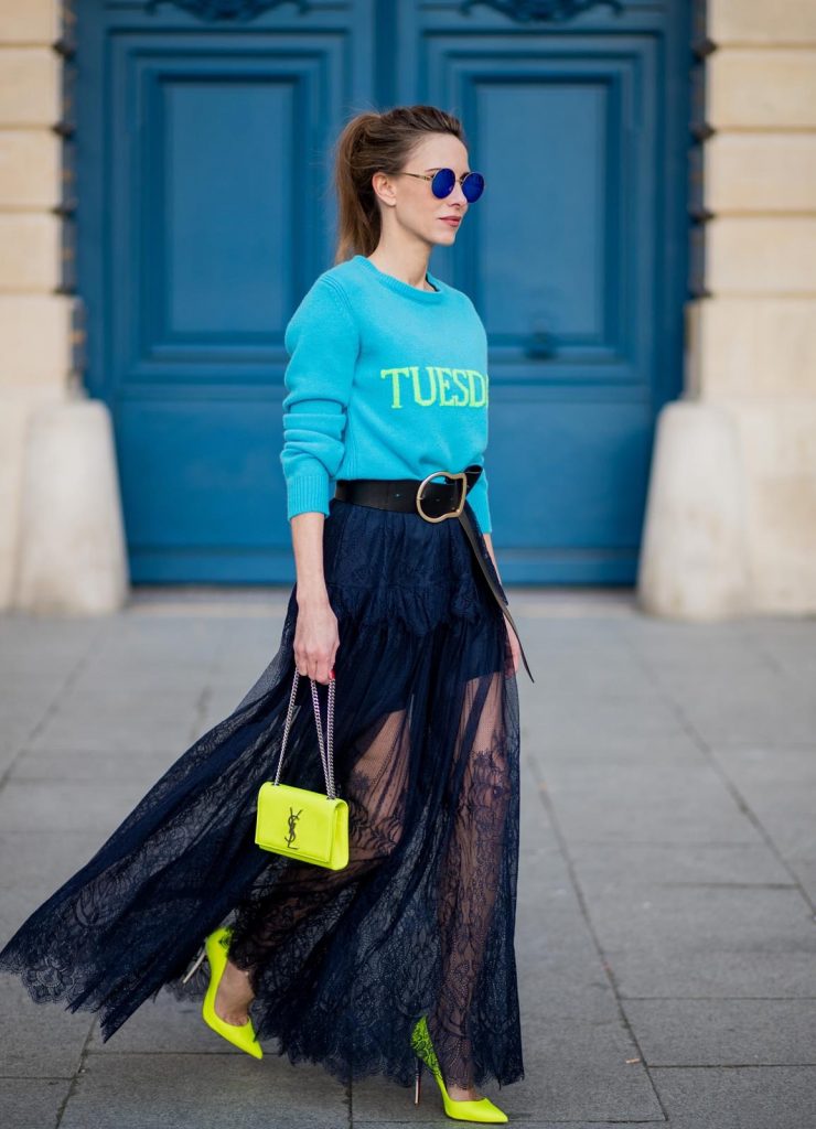 Alexandra Lapp wearing a turquoise pullover with a neon print Tuesday by Alberta Ferretti, a playful dress in black floral lace from Self-Portrait, black waist belt with big buckle from Dorothee Schumacher, blue mirrored sunglasses from Mykita, neon yellow pumps from Christian Louboutin and matching neon yellow handbag from Yves Saint Laurent is seen on February 28, 2018 in Paris, France.