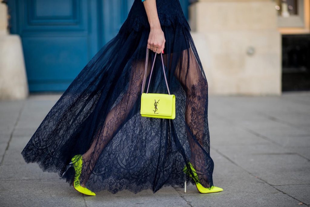 Alexandra Lapp wearing a turquoise pullover with a neon print Tuesday by Alberta Ferretti, a playful dress in black floral lace from Self-Portrait, black waist belt with big buckle from Dorothee Schumacher, blue mirrored sunglasses from Mykita, neon yellow pumps from Christian Louboutin and matching neon yellow handbag from Yves Saint Laurent is seen on February 28, 2018 in Paris, France.