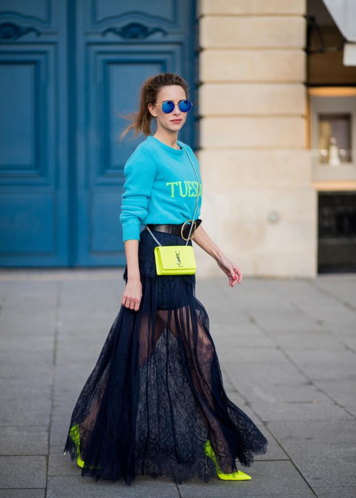 Alexandra Lapp wearing a turquoise pullover with a neon print Tuesday by Alberta Ferretti, a playful dress in black floral lace from Self-Portrait, black waist belt with big buckle from Dorothee Schumacher, blue mirrored sunglasses from Mykita, neon yellow pumps from Christian Louboutin and matching neon yellow handbag from Yves Saint Laurent is seen on February 28, 2018 in Paris, France.