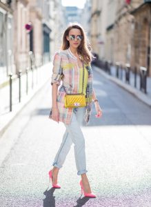 PARIS, FRANCE - MARCH 02: Alexandra Lapp wearing pastel tweed, a long tweed blazer in pastel colors from Airfield, a silk top in bright yellow from Jadicted, light blue boyfriend jeans by Airfield, a neon yellow Chanel bag, neon pink high heels from Christian Louboutin and sunglasses from Le Specs is seen on March 2, 2018 in Paris, France.