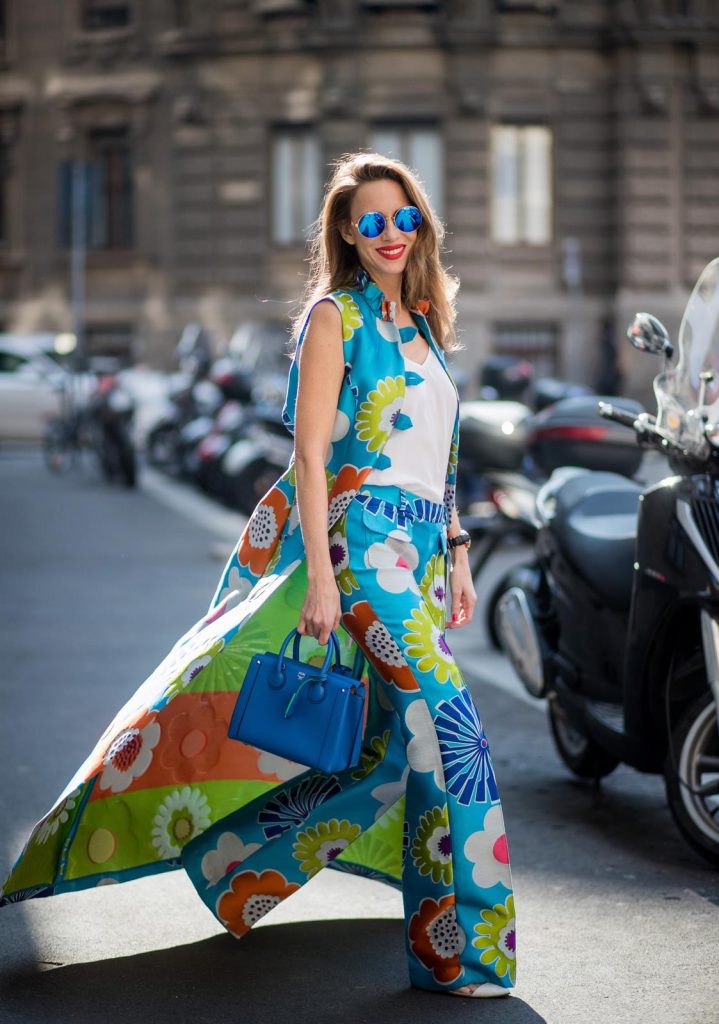 Alexandra Lapp in Seventies Style wearing flower power silk jacquard pants in multicolor with a long leg by Talbot Runhof with matching long vest made of flower power jacquard in multicolor, white silk shirt from Jadicted, blue neo Milla tote bag, Pigalle Follies pumps by Christian Louboutin and blue round sunglasses from Mykita seen during Milan Fashion Week Fall/Winter 2018/19 on February 21, 2018 in Milan, Italy.