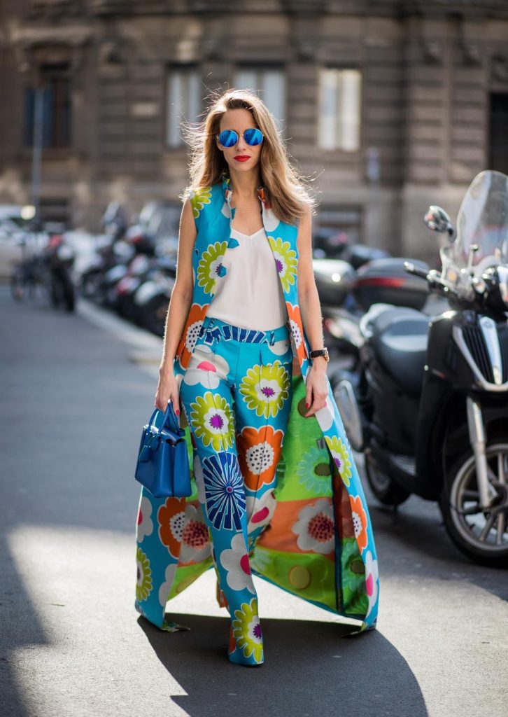 Alexandra Lapp in Seventies Style wearing flower power silk jacquard pants in multicolor with a long leg by Talbot Runhof with matching long vest made of flower power jacquard in multicolor, white silk shirt from Jadicted, blue neo Milla tote bag, Pigalle Follies pumps by Christian Louboutin and blue round sunglasses from Mykita seen during Milan Fashion Week Fall/Winter 2018/19 on February 21, 2018 in Milan, Italy.