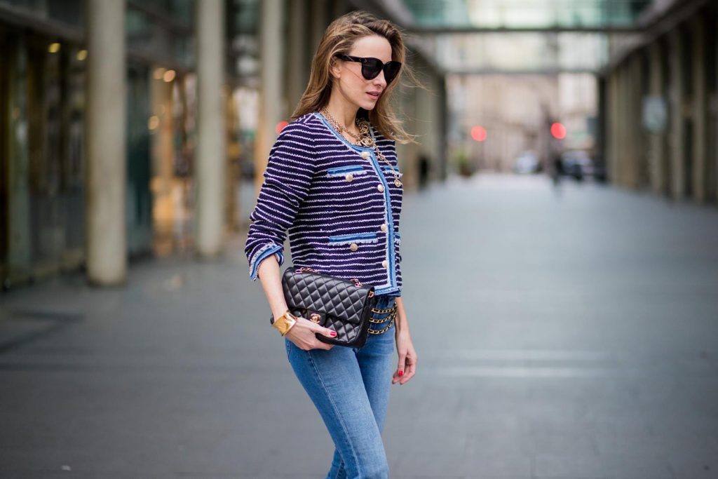 Alexandra Lapp wearing Chanel Vintage: striped tweed jacket in marine tones and flared jeans from Steffen Schraut, a vintage belt with chains and vintage bracelets from Chanel, denim pumps from Christian Louboutin, a 2.55 Chanel handbag in black and black Celine sunglasses is seen on February 27, 2018 in Paris, France. 