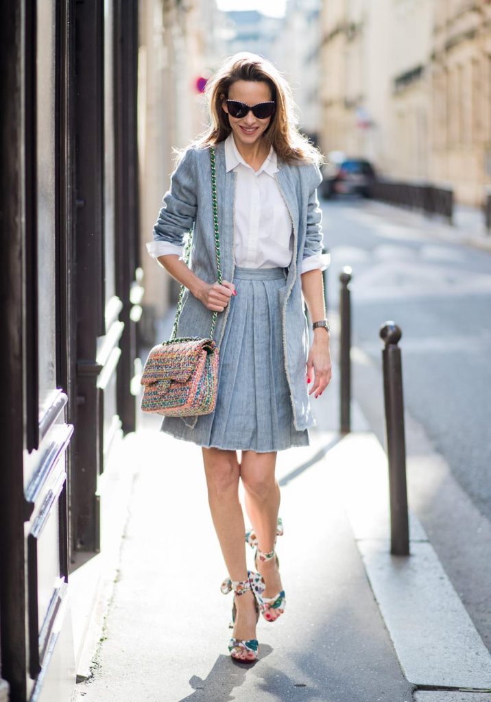 Alexandra Lapp in Linen Chic wearing a linen open front blazer with a fringed hem line in a denim optic and a high waist linen pleated skirt in denim optic and a fringed hem line by Steffen Schraut, a white blouse from Steffen Schraut, a 2.55 Chanel bag in multicolor, high heel sandals with a long satin bow with fruit motifs by Christian Louboutin and brown Chanel sunglasses with pearls seen on March 2, 2018 in Paris, France.