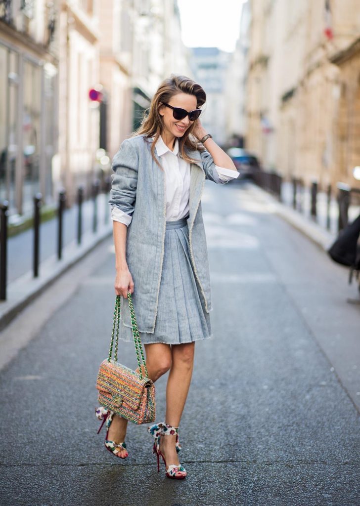 Alexandra Lapp in Linen Chic wearing a linen open front blazer with a fringed hem line in a denim optic and a high waist linen pleated skirt in denim optic and a fringed hem line by Steffen Schraut, a white blouse from Steffen Schraut, a 2.55 Chanel bag in multicolor, high heel sandals with a long satin bow with fruit motifs by Christian Louboutin and brown Chanel sunglasses with pearls seen on March 2, 2018 in Paris, France.