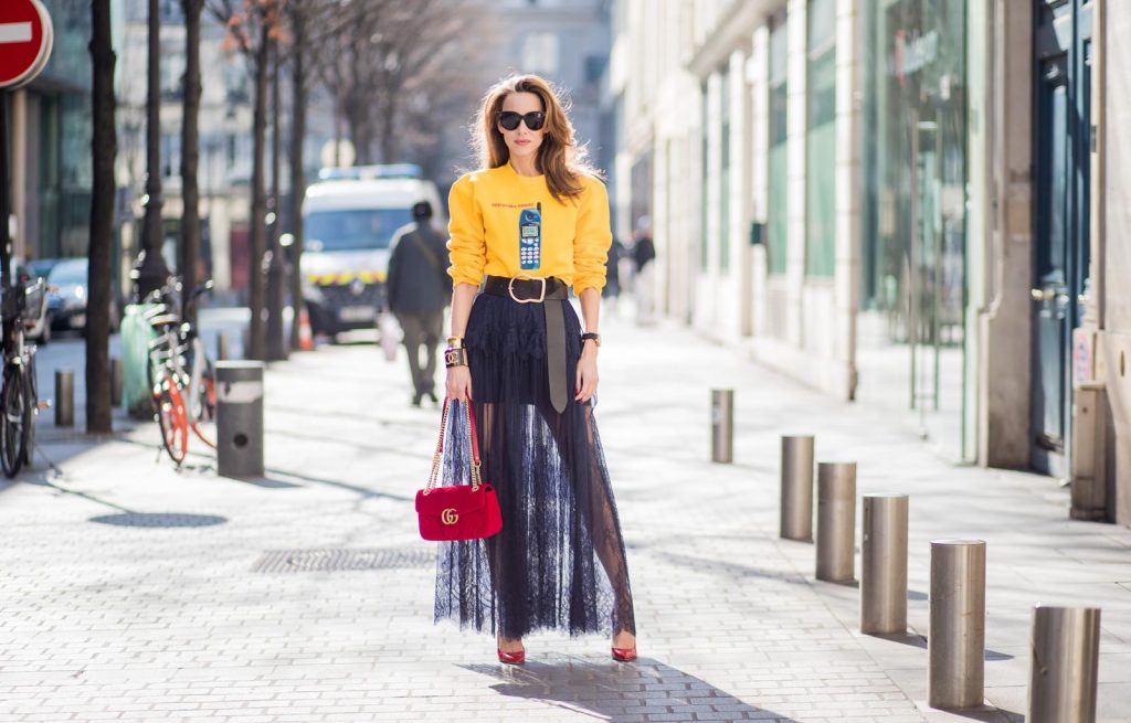 Alexandra Lapp in handmade print Wodka Ogurez sweater in yellow with handmade Nokia phone print, long dark blue Self-Portrait lace dress underneath, Dorothee Schumacher waist belt with big golden buckle, red patent Gianvito Rossi pumps, Chanel bracelet with golden CC sign, golden vintage Chanel bracelet, red velvet Gucci Marmont bag and Celine Audrey sunglasses during Paris Fashion Week Womenswear Fall/Winter 2018/2019 on March 3, 2018 in Paris, France.