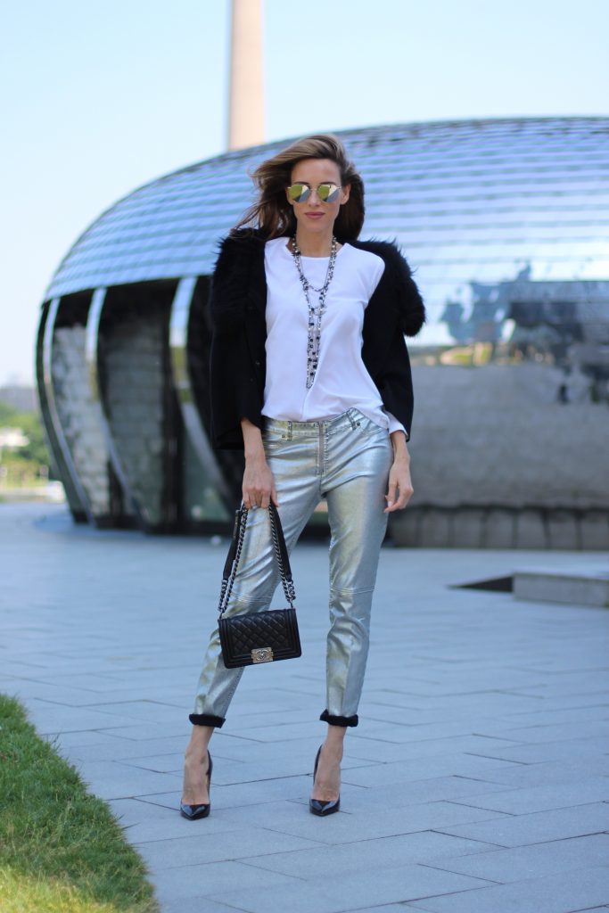 Model and Blogger Alexandra Lapp wearing silver denim pants from Airfield, black knit and fur cape from Airfield, black Boy Bag from Chanel, Chanel vintage necklace, silver sunglasses by Le Specs, white silk shirt from Jades and black lacquer Pigalle pumps from Christian Louboutin.