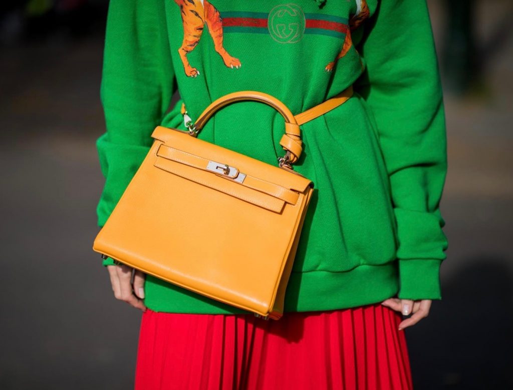 Alexandra Lapp in a Hermès Kelly Look wearing a green tiger print Gucci logo hoodie, a red pleated skirt by SET, a Hermes Birkin 30 bag in orange, Pigalle Follies pumps by Christian Louboutin and green mirrored Ray Ban sunglasses on May 3, 2018 in Duesseldorf, Germany. 