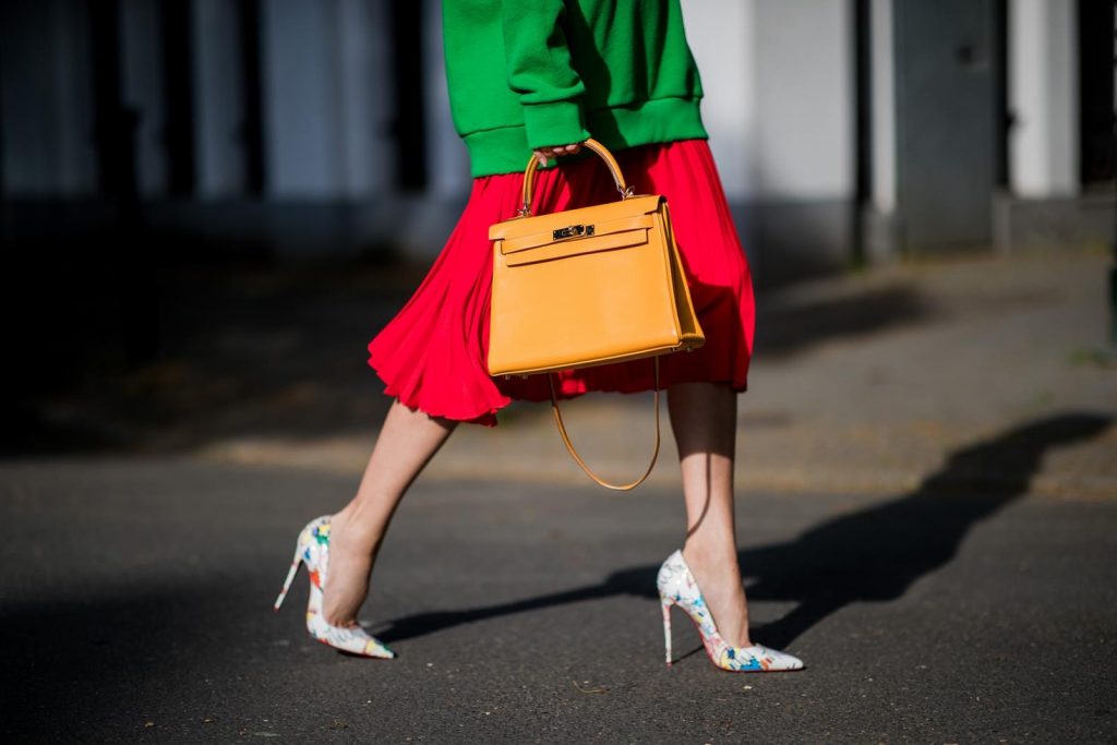 Alexandra Lapp in a Hermès Kelly Look wearing a green tiger print Gucci logo hoodie, a red pleated skirt by SET, a Hermes Birkin 30 bag in orange, Pigalle Follies pumps by Christian Louboutin and green mirrored Ray Ban sunglasses on May 3, 2018 in Duesseldorf, Germany. 