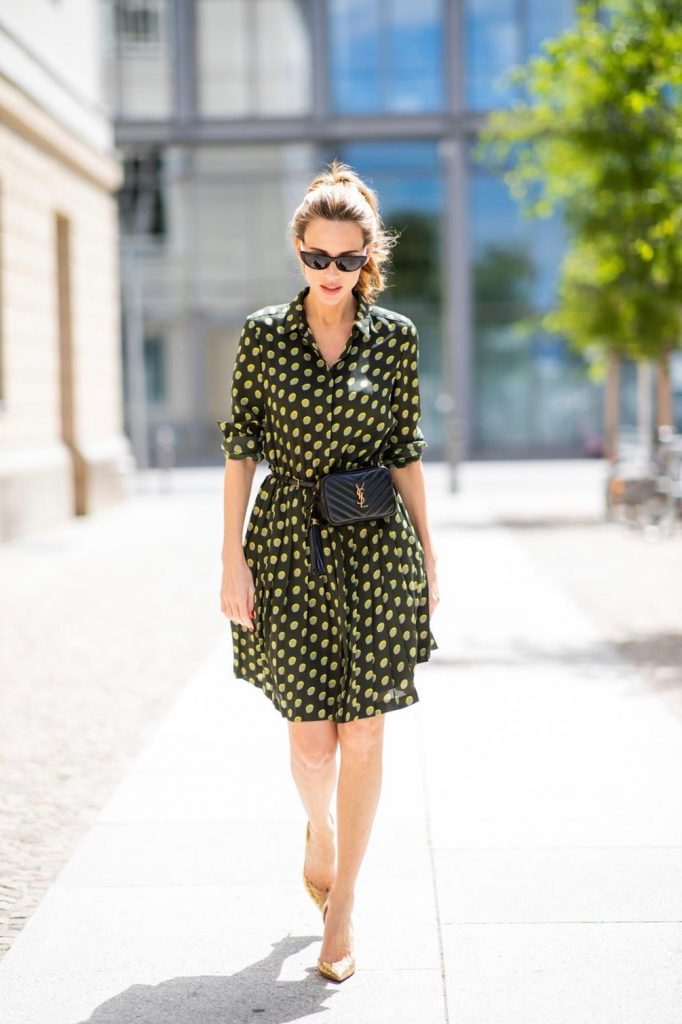 Alexandra Lapp is seen in a Waist Belt Bag Look wearing a knee length dark green dress with green and yellow dots from Steffen Schraut, the Lou Belt Bag in black by Saint Laurent, the golden Iriza glitter pumps by Christian Louboutin and two tone sunglasses from State x Cotw in black white on July 13, 2018 in Berlin, Germany.