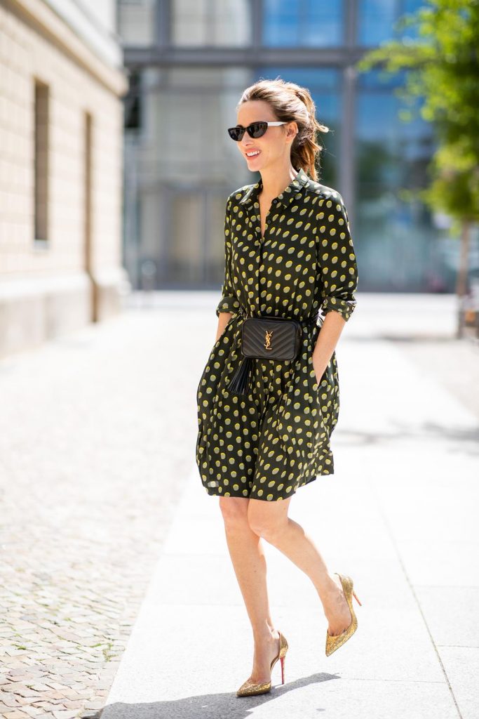 Alexandra Lapp is seen in a Waist Belt Bag Look wearing a knee length dark green dress with green and yellow dots from Steffen Schraut, the Lou Belt Bag in black by Saint Laurent, the golden Iriza glitter pumps by Christian Louboutin and two tone sunglasses from State x Cotw in black white on July 13, 2018 in Berlin, Germany.