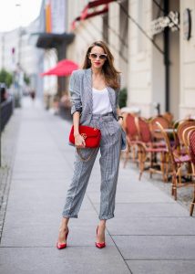 Alexandra Lapp for Big Dream | Riani wearing a checkered suit combination in black and white with a long blazer and high waist pants with an integrated belt both from Riani, a white silk top from Jadicted, red lacquer Gianvito Rossi pumps, red velvet GG Marmont Gucci handbag, vintage Gucci sunglasses and an IWC watch during the Berlin Fashion Week July 2018 on July 6, 2018 in Berlin, Germany.