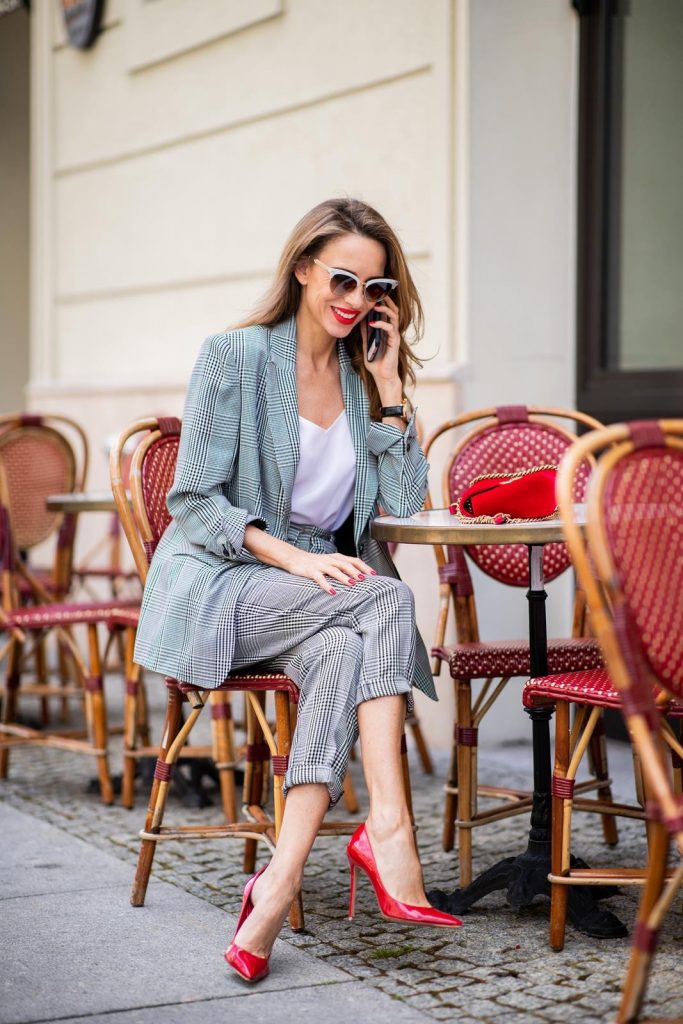 Alexandra Lapp for Big Dream | Riani wearing a checkered suit combination in black and white with a long blazer and high waist pants with an integrated belt both from Riani, a white silk top from Jadicted, red lacquer Gianvito Rossi pumps, red velvet GG Marmont Gucci handbag, vintage Gucci sunglasses and an IWC watch during the Berlin Fashion Week July 2018 on July 6, 2018 in Berlin, Germany.