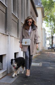 Model and Blogger Alexandra Lapp wearing a Céline Box Bag Look with a wool coat with fur collar in taupe, a light white wool sweater by Zara, grey Levi’s jeans, camouflage Gianvito Rossi pumps, vintage Gucci sunglasses and a light grey Céline box bag in Düsseldorf, Germany.