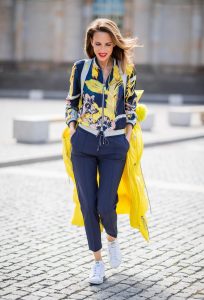 Alexandra Lapp in a Floral Jacket | Yellow Coat Look is seen wearing a blouson jacket with floral print, blue drawstring pants and a bright yellow duffle coat with a yellow fur hood from Airfield, Céline sunglasses in black, white Stan Smith Adidas sneakers with green details during the Berlin Fashion Week July 2018 on July 6, 2018 in Berlin, Germany.