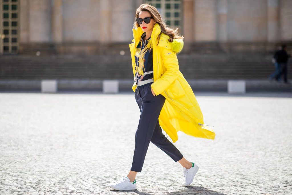 Alexandra Lapp in a Floral Jacket | Yellow Coat Look is seen wearing a blouson jacket with floral print, blue drawstring pants and a bright yellow duffle coat with a yellow fur hood from Airfield, Céline sunglasses in black, white Stan Smith Adidas sneakers with green details during the Berlin Fashion Week July 2018 on July 6, 2018 in Berlin, Germany.