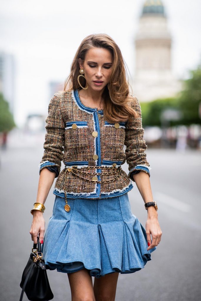 Alexandra Lapp in a Pleated Denim Skirt Look wearing a short tweed boucle jacket with denim from Steffen Schraut, a denim shirt from H&M, a denim pleated skirt from Balmain, vintage jewelry from Chanel, High Heel sandals 'Sandale Du Desert' in denim blue with a printed satin bow from Christian Louboutin and the Peekaboo Essentially Fendi handbag in black during the Berlin Fashion Week July 2018 on July 6, 2018 in Berlin, Germany.