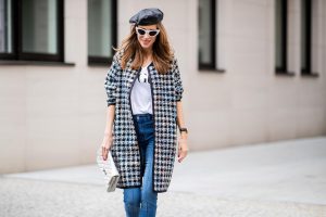 Alexandra Lapp wearing an oversized college jacket look with an oversized checkered college jacket from Steffen Schraut, stirrup denim pants from Steffen Schraut, a white V-neck t-shirt saying Vogue on the front from Your&Self, High Heel Sandals Sandale Du Desert in denim blue with a printed satin bow from Christian Louboutin, a silver Chanel handbag, white cat-eye sunglasses from YSL - Saint Laurent and Eugenia Kim leather basque Cher Barett on July 13, 2018 in Berlin, Germany.