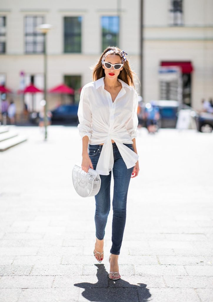 Alexandra Lapp in a Headband Style wearing La Chemise Olhao in off white by Jacquemus, blue AG Adriano Goldschmied denim, white Inez leather sandals by Saint Laurent, white Gaia's Ark bag by Cult Gaia, white Saint Laurent New Wave 213 Lily Sunglasses and a vintage Dior headband during the Berlin Fashion Week July 2018 on July 6, 2018 in Berlin, Germany.