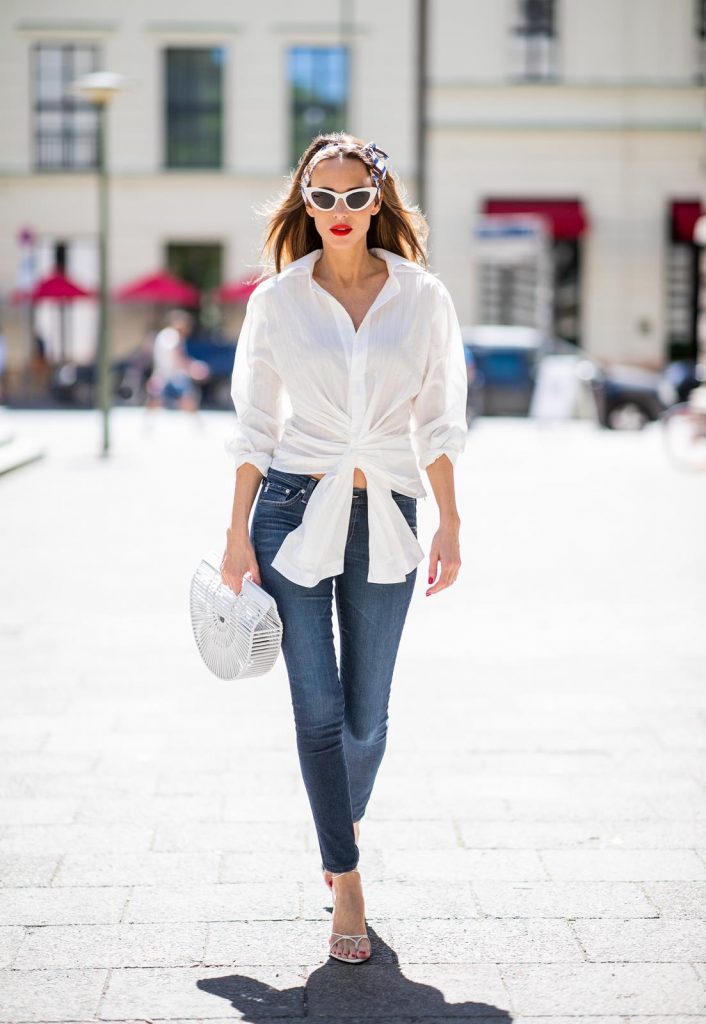 Alexandra Lapp in a Headband Style wearing La Chemise Olhao in off white by Jacquemus, blue AG Adriano Goldschmied denim, white Inez leather sandals by Saint Laurent, white Gaia's Ark bag by Cult Gaia, white Saint Laurent New Wave 213 Lily Sunglasses and a vintage Dior headband during the Berlin Fashion Week July 2018 on July 6, 2018 in Berlin, Germany.