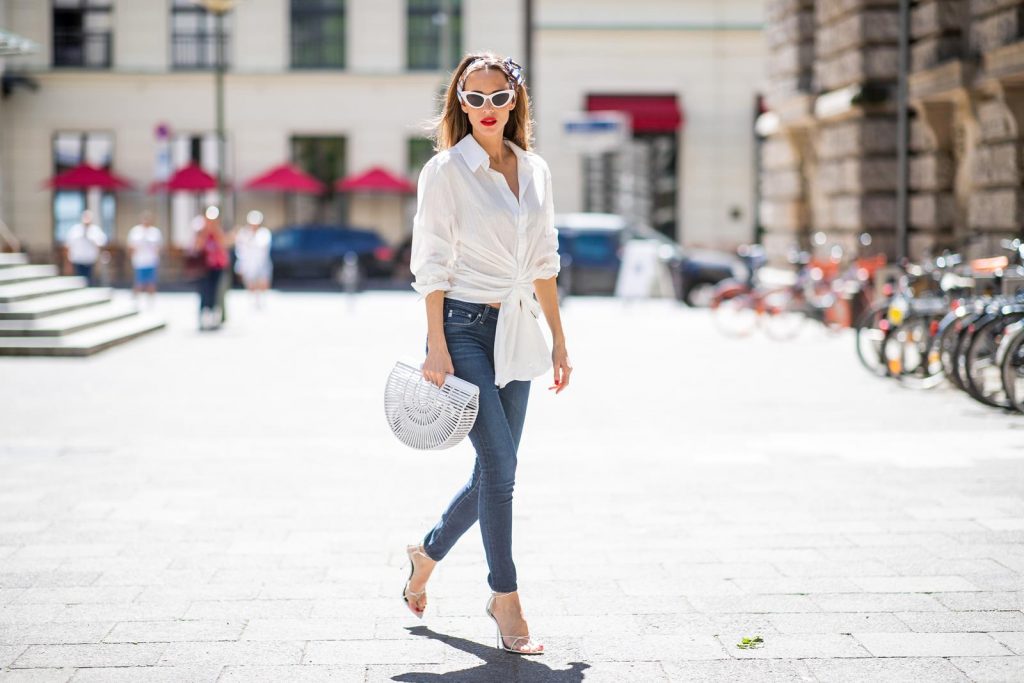 Alexandra Lapp in a Headband Style wearing La Chemise Olhao in off white by Jacquemus, blue AG Adriano Goldschmied denim, white Inez leather sandals by Saint Laurent, white Gaia's Ark bag by Cult Gaia, white Saint Laurent New Wave 213 Lily Sunglasses and a vintage Dior headband during the Berlin Fashion Week July 2018 on July 6, 2018 in Berlin, Germany.