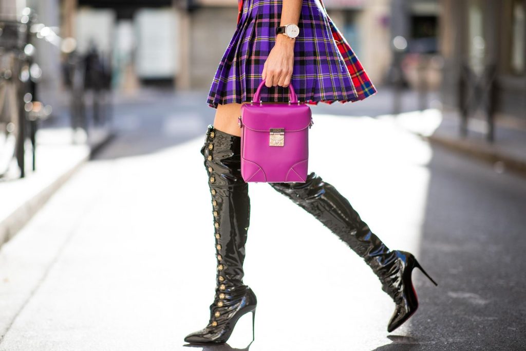 Alexandra Lapp in a Kilt Skirt Look wearing a long black boyfriend oversized blazer by Saint Laurent, a handmade Wodka Ogurez T-Shirt with a hand-painted print, a pleated patchwork tartan mini wool skirt from Versace, Frenchissima Alta Overknees in patent soft black leather by Christian Louboutin, Soft Berlin Crossbody Bag in Viva Lilac from MCM, vintage Chanel bakerboy cap in black and Neenah sunglasses from State Optical in black white is seen during Paris Fashion Week Womenswear Spring/Summer 2019 on September 29, 2018 in Paris, France.
