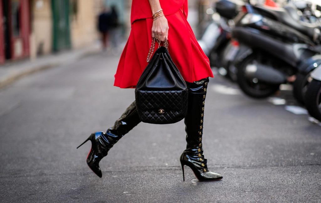 Alexandra Lapp in a Vinyl Overknee Boots Look wearing a long waisted blazer in red by Steffen Schraut, red high waist skirt with attached ribbon by Steffen Schraut, black patent leather waist belt by Gucci, Frenchissima Alta Overknees in patent soft black leather by Christian Louboutin, vintage Chanel backpack in black and red cat-eyed sunglasses by Céline during Paris Fashion Week Womenswear Spring/Summer 2019 on September 24, 2018 in Paris, France.