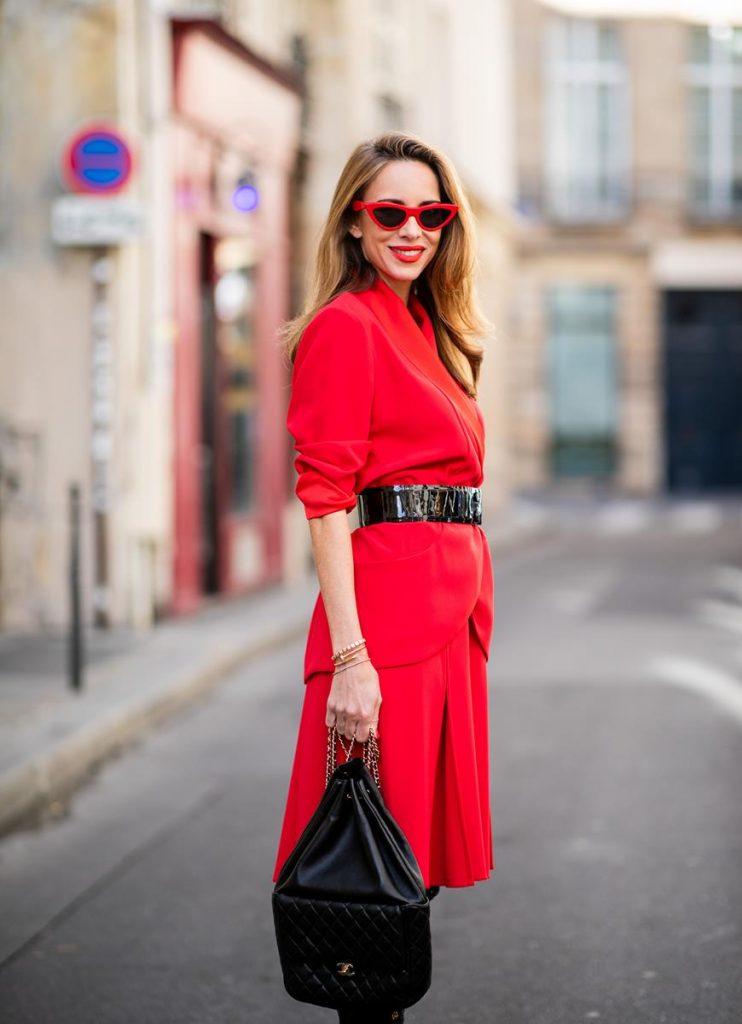 Alexandra Lapp in a Vinyl Overknee Boots Look wearing a long waisted blazer in red by Steffen Schraut, red high waist skirt with attached ribbon by Steffen Schraut, black patent leather waist belt by Gucci, Frenchissima Alta Overknees in patent soft black leather by Christian Louboutin, vintage Chanel backpack in black and red cat-eyed sunglasses by Céline during Paris Fashion Week Womenswear Spring/Summer 2019 on September 24, 2018 in Paris, France.