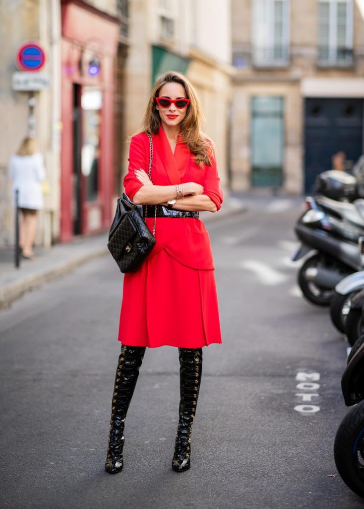 Alexandra Lapp in a Vinyl Overknee Boots Look wearing a long waisted blazer in red by Steffen Schraut, red high waist skirt with attached ribbon by Steffen Schraut, black patent leather waist belt by Gucci, Frenchissima Alta Overknees in patent soft black leather by Christian Louboutin, vintage Chanel backpack in black and red cat-eyed sunglasses by Céline during Paris Fashion Week Womenswear Spring/Summer 2019 on September 24, 2018 in Paris, France.