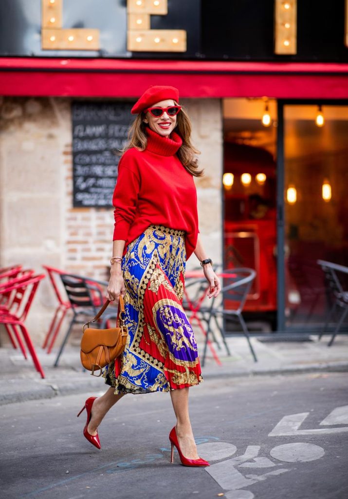 Alexandra Lapp seen in a Versace Skirt Look wearing a pleated printed midi skirt from Versace, a long red cashmere turtle neck pullover from Falconeri, a vintage Dior saddle bag in cognac, red pumps from Gianvito Rossi, a beret cap in red from Zara, red cat-eye shaped sunglasses from Celine during Paris Fashion Week Womenswear Spring/Summer 2019 on September 29, 2018 in Paris, France.
