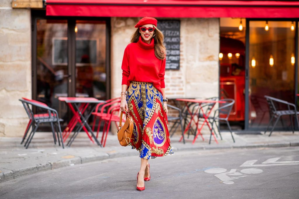 Alexandra Lapp seen in a Versace Skirt Look wearing a pleated printed midi skirt from Versace, a long red cashmere turtle neck pullover from Falconeri, a vintage Dior saddle bag in cognac, red pumps from Gianvito Rossi, a beret cap in red from Zara, red cat-eye shaped sunglasses from Celine during Paris Fashion Week Womenswear Spring/Summer 2019 on September 29, 2018 in Paris, France.