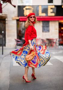 Alexandra Lapp seen in a Versace Skirt Look wearing a pleated printed midi skirt from Versace, a long red cashmere turtle neck pullover from Falconeri, a vintage Dior saddle bag in cognac, red pumps from Gianvito Rossi, a beret cap in red from Zara, red cat-eye shaped sunglasses from Celine during Paris Fashion Week Womenswear Spring/Summer 2019 on September 29, 2018 in Paris, France.