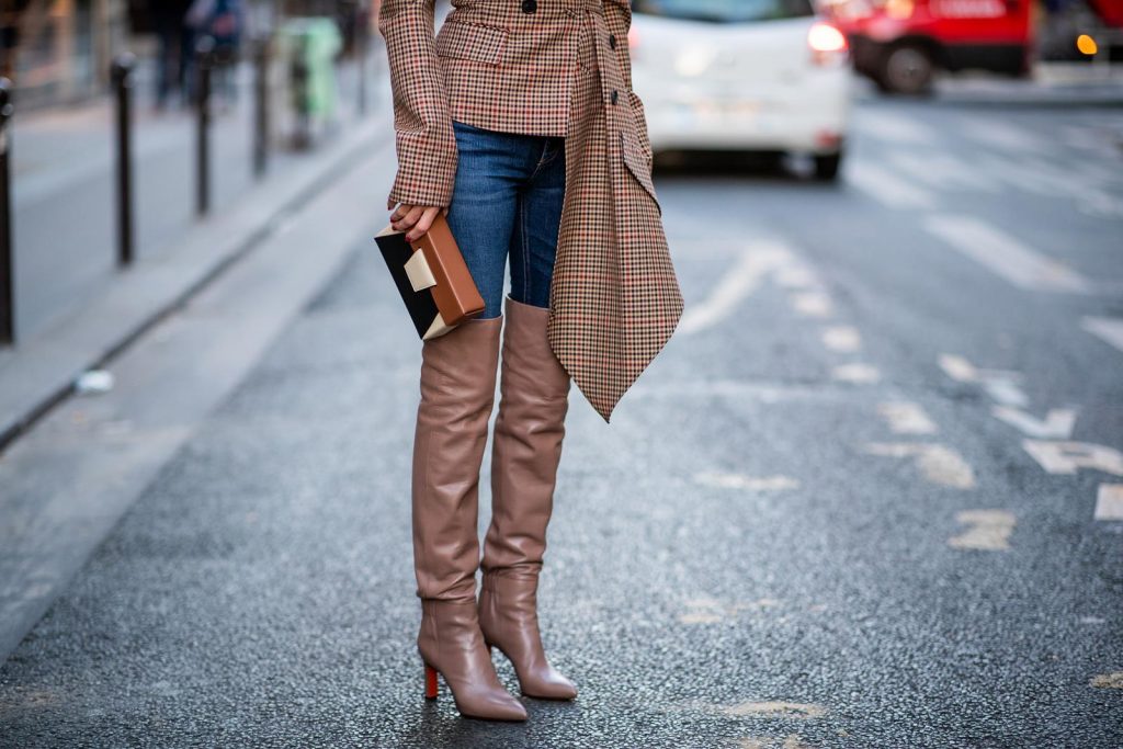 Alexandra Lapp wearing an Off-Shoulder Blazer Look with a plaid asymmetric off shoulder blazer from Monse, dark blue jeans from Rag & Bone, over knee boots in soft pink from Santoni, a Yuzefi Lola leather belt bag in brownish and black tones and brown sunglasses from State Optical during Paris Fashion Week Womenswear Spring/Summer 2019 on September 26, 2018 in Paris, France.