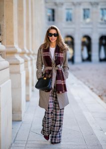 Alexandra Lapp in a Layered Look wearing a plaid oversized coat from SET fashion, a white T-Shirt from Vince, a Glenchek style scarf in dark red tones, wide plaid pants with a long leg in blue and brown tones from Tory Burch, boots in bordeaux from Gianvito Rossi and black Audrey sunglasses from Celine during Paris Fashion Week Womenswear Spring/Summer 2019 on September 27, 2018 in Paris, France.