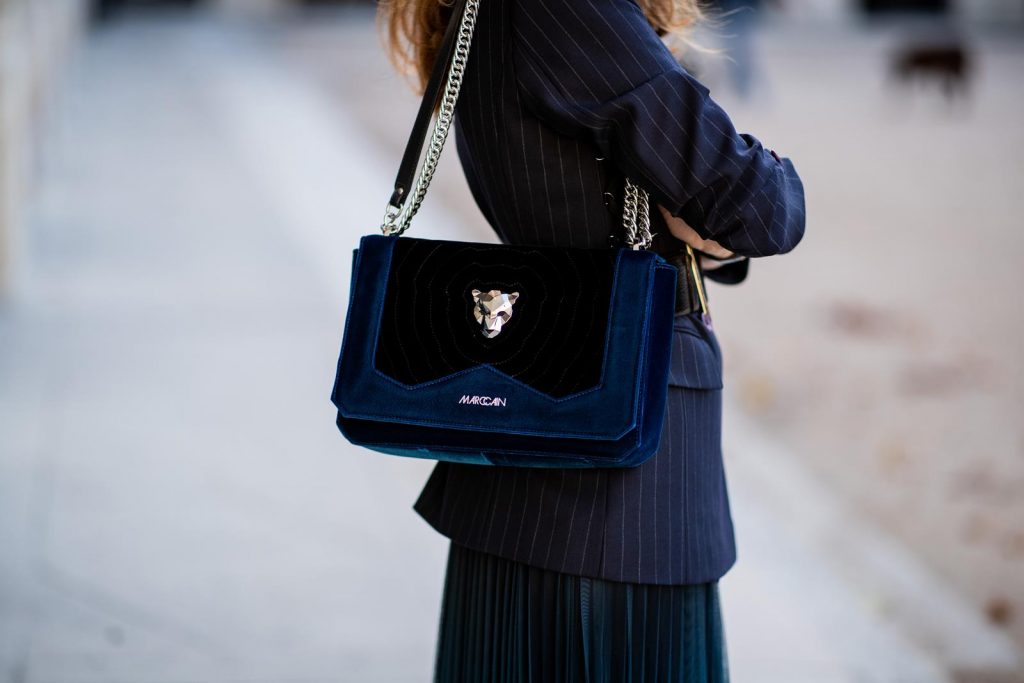 Alexandra Lapp in an All Blue Everything Look wearing a blue pleated skirt, navy striped blazer with belt and blue velvet bag all by Marc Cain, black heels from Christian Louboutin, a black lacquer waist belt by Dolce & Gabbana and black Audrey sunglasses by Céline seen during Paris Fashion Week Womenswear Spring/Summer 2019 on September 25, 2018 in Paris, France.