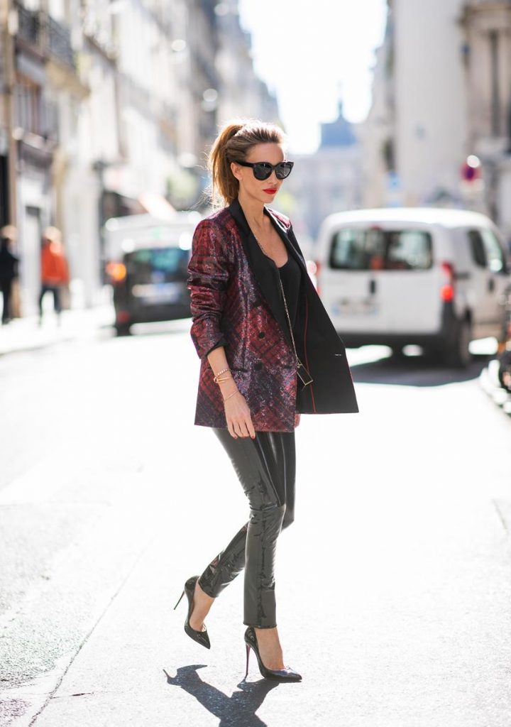 Alexandra Lapp in a Faux Leather Pants Look wearing a long shiny sequin trimmed plaid blazer from Tommy Hilfiger, slim cut black vinyl pants from Rag & Bone, a black satin top from Jadicted, black lacquer pumps from Christian Louboutin, a Roger Vivier Stars Rivets leather cigarette case with a long golden chain and the black Audrey sunglasses from Celine during Paris Fashion Week Womenswear Spring/Summer 2019 on September 25, 2018 in Paris, France.