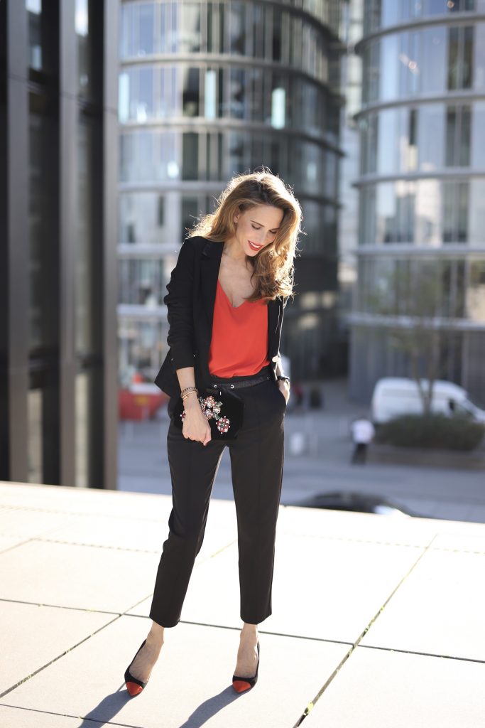 Alexandra Lapp in a Pop of Red Look wearing a stunning black blazer and pants combo from Airfield, mixed with a bright red silk top by Jadicted, an embroidered bag by Roger Vivier and a pair of Manolo Blahnik spiked heels.